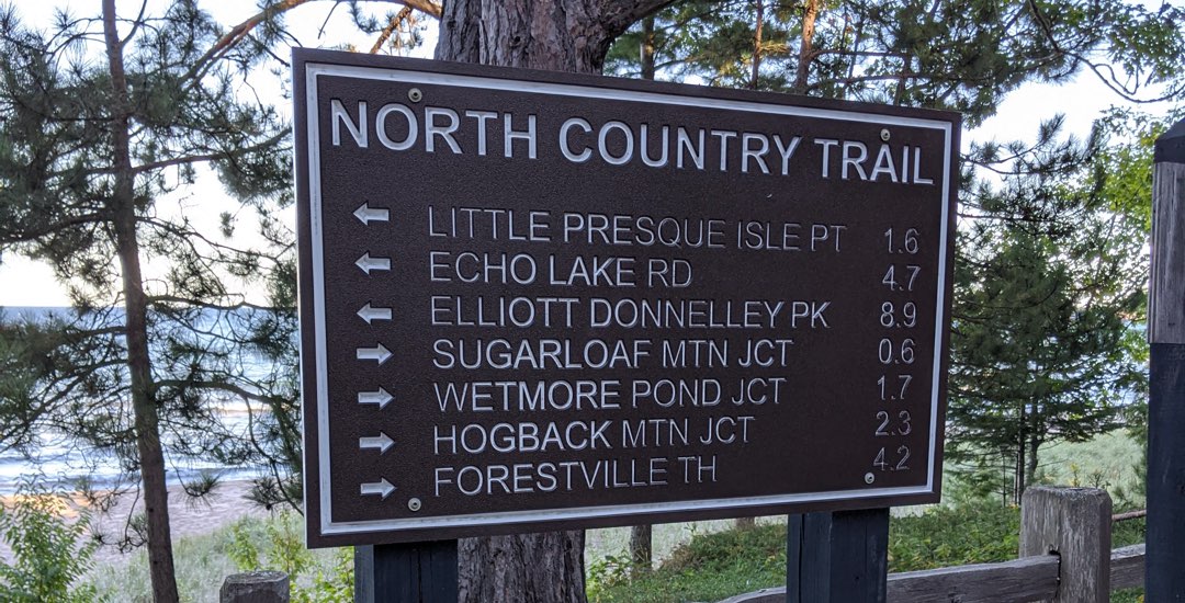 Sign board showing directions for Marquette's North Country trails with distance